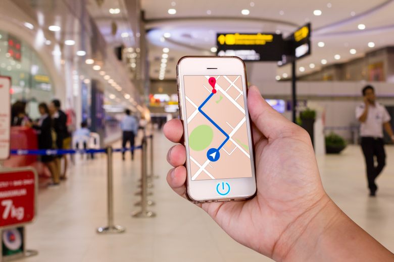 Man is holding mobile phone with map gps navigation in the airport.