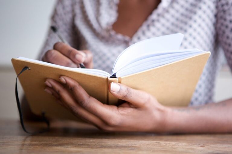 woman journaling on a notebook as a daily practice for betterment